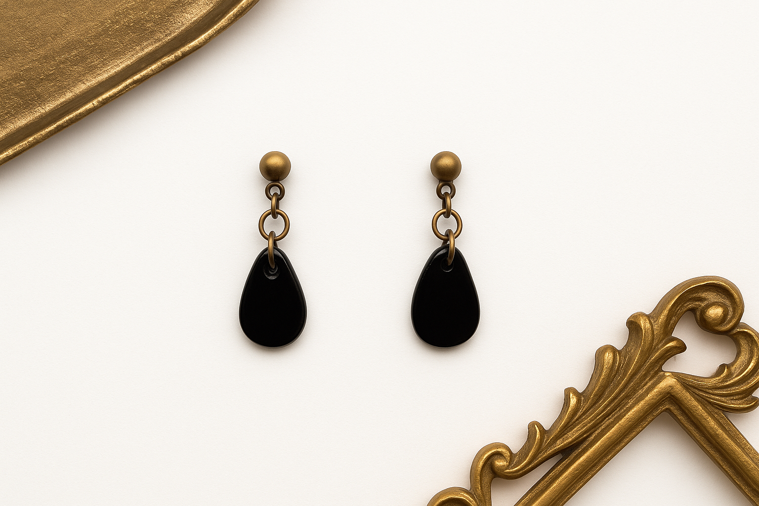 Minimalist black jewellery styled with antique gold accents on a clean background.